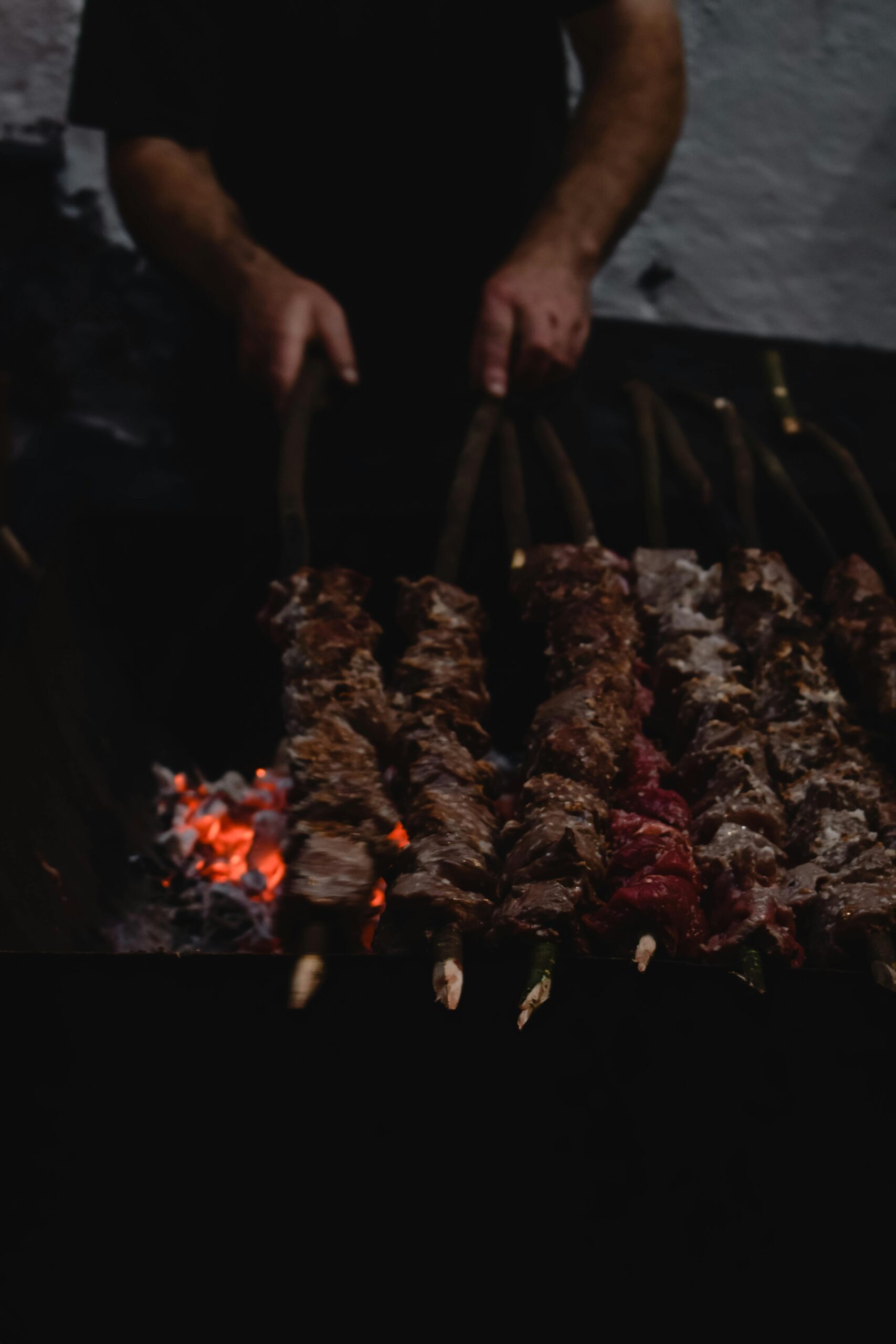 A close-up of skewered meat cooking over an open flame, showcasing traditional Espetada preparation.